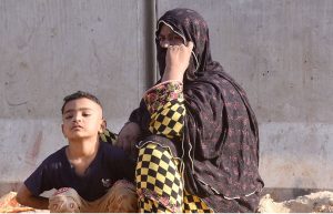 Security personnel stand as rescue workers search the debris for fire victims at Gul Plaza.