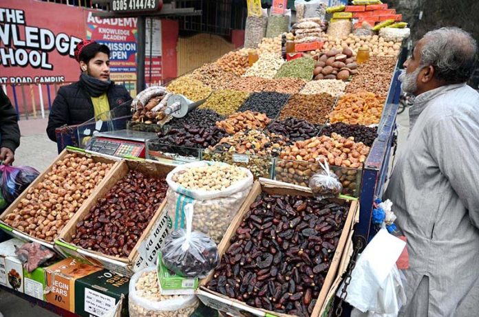 A young vendor arranging and selling the different kinds of Dry fruits to attract the customers on the roadside setup in the Provincial Capital