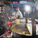A vendor selling chicken soup at his roadside setup amid cold weather grips the city at night