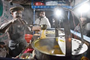 A vendor selling chicken soup at his roadside setup amid cold weather grips the city at night
