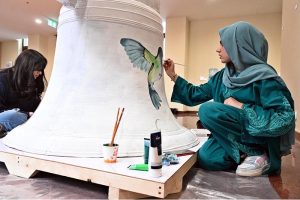 An artist paints on a bell during the launch of "Freedom 250 Liberty Bell" Initiative "Let Freedom Ring" at Lincein Corner in New USEFP building