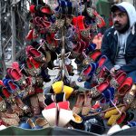 A vendor waiting the customers for selling the colorful handmade children shoes on his roadside setup outside the Naulakha Bazaar