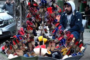 A vendor waiting the customers for selling the colorful handmade children shoes on his roadside setup outside the Naulakha Bazaar
