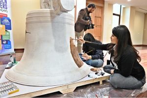 An artist paints on a bell during the launch of "Freedom 250 Liberty Bell" Initiative "Let Freedom Ring" at Lincein Corner in New USEFP building