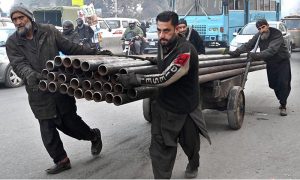Labourers pulling and pushing handcart loaded with heavy Iron pipes to deliver in a local market