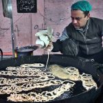 A vendor prepares sweet food item Jalebi to the customers at his roadside setup in the Provincial Capital.