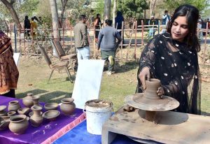 A student tries to make a clay pot at a stall during the Gur Mela organized by the Directorate of Farms at the University of Agriculture, Faisalabad.