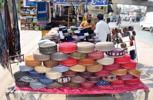 A vendor displays traditional embroidered caps at a roadside stall, during Holy month of Ramazan to attract the customers.