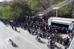Motorcyclists stand in a long queue at Kachnar Park for mandatory M-Tag registration under the second phase of the capital’s vehicle tagging drive.
