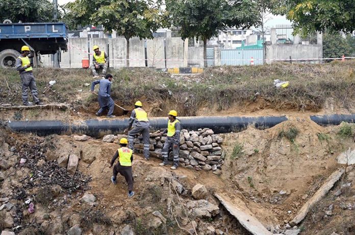 Workers are busy placing stones under the gas pipeline to support it during maintenance work in the Federal Capital
