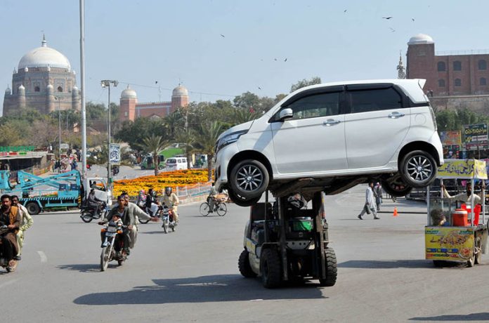 A traffic warden removing a wrongly parked car with the help of a forklift at Ghanta Ghar Chowk to ensure smooth flow of traffic in the City