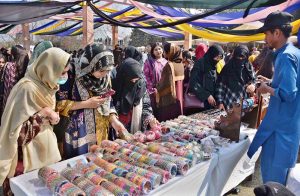 A student tries to make a clay pot at a stall during the Gur Mela organized by the Directorate of Farms at the University of Agriculture, Faisalabad.