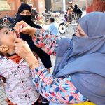 A lady health worker administering polio drops to a child during anti-polio campaign at Partabad Hospital
