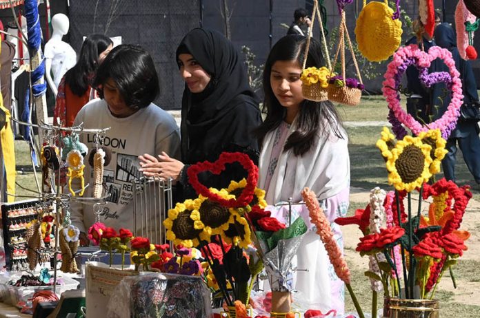 Girls look at artificial jewelry displayed for sale during the Faiz Festival at Alhamra