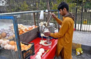 A vendor busy roasting sweet potatoes on his handcart to attract the customers