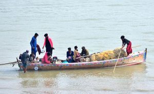 Fishermen are busy catching fish on the boat at Indus River.