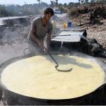 A worker extracting sugarcane juice by a machine to make Jiggery at his roadside setup