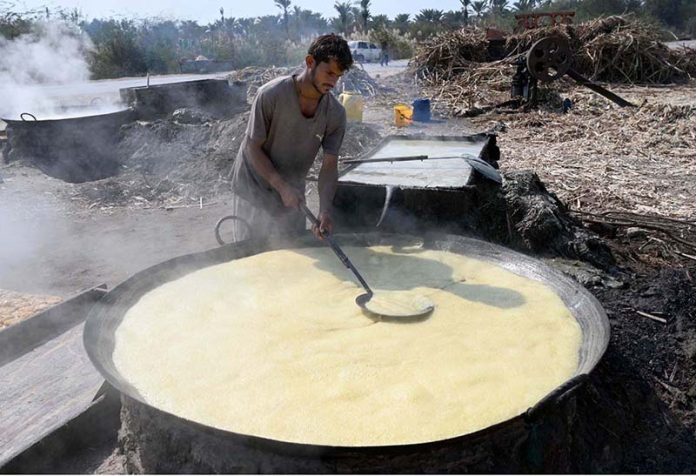 A worker extracting sugarcane juice by a machine to make Jiggery at his roadside setup