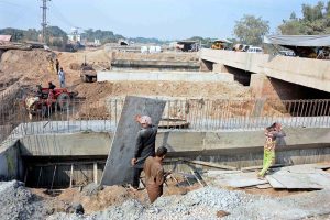 Workers are busy construction work during the extension of the Sikandari Nala Bridge on Head Muhammad Wala Road as part of an ongoing development project