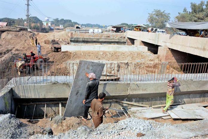 Workers are busy construction work during the extension of the Sikandari Nala Bridge on Head Muhammad Wala Road as part of an ongoing development project