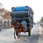 A donkey cart holder is on his way loaded with empty drums