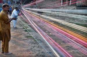 Workers prepare kite-flying string ahead of the upcoming Basant festival in the Provincial Capital