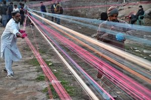 Workers prepare kite-flying string ahead of the upcoming Basant festival in the Provincial Capital