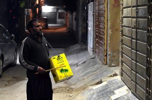A drum beater walks through a residential area, beating his iron drum to wake people for Sehri during the holy fasting month of Ramazan-ul-Mubarak