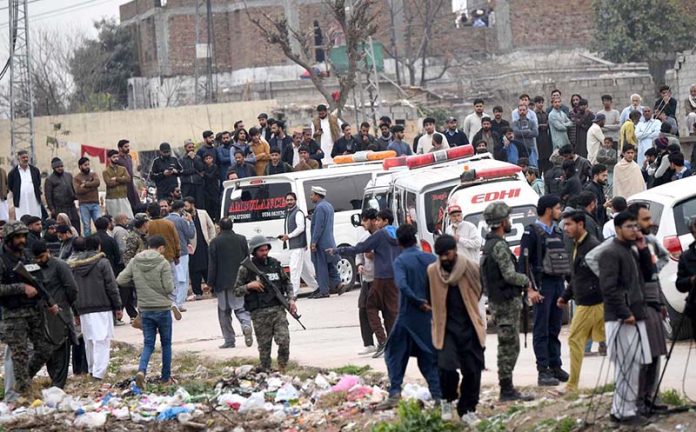 People and security personnel gather at the blast site after a powerful bomb blast at the gate of Tarlai Imambargah killed and injured several people in the Shehzad Town area of the federal capital