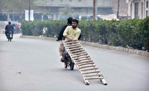 Motorcyclists carry a bamboo ladder in a hazardous manner, posing serious risks to other road users.