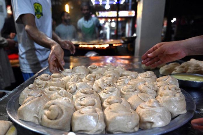 Vendors preparing traditional food stuff (Parathas) for Sehri to the customers at local market during Holy Fasting Month of Ramazan ul Mubarak