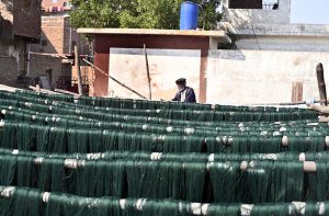 A labourer arranging thread for drying purpose after preparing at local factory.