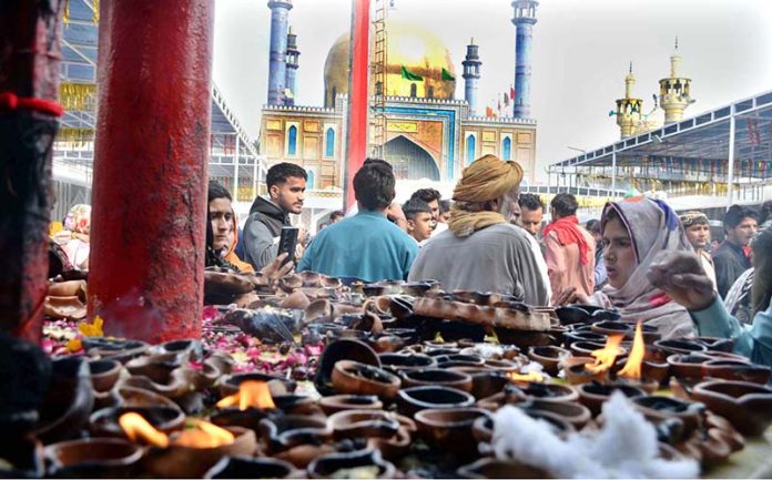 Devotees light oil lamps at shrine of Lal Shahbaz Qalandar on the occasion of 774th Urs celebration