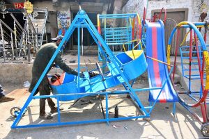 A worker busy in coloring the swing at his workplace.