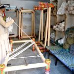 A worker knitting traditional beds (charpai) at his workplace.