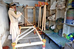 A worker knitting traditional beds (charpai) at his workplace.