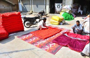 Workers engaged in quilt-making at their workshop as demand rises due to falling temperatures in the city.