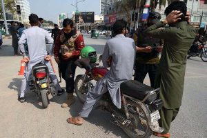 Security personnel conduct security checks of motorcyclists and verify their documents while maintaining high alert on Saddar Road in the provincial capital.