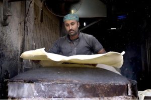 A worker prepares samosa patti on a huge tawa, rolling the dough by hand step by step ahead of Ramadan-ul-Mubarak.