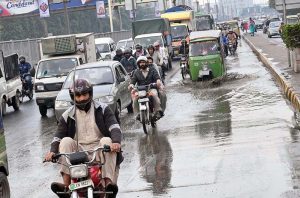 A motorcyclist carefully navigates through accumulated water during a light drizzle on Ferozepur Road in the provincial capital.