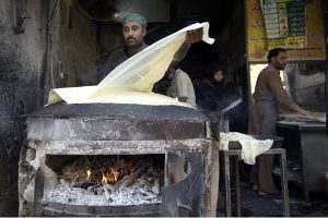 A worker prepares samosa patti on a huge tawa, rolling the dough by hand step by step ahead of Ramadan-ul-Mubarak.