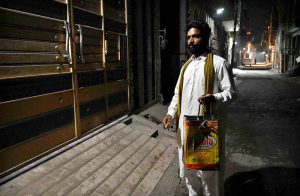 A Sehri awaker walks through the streets of a residential area, beating his iron drum to wake residents for Sehri during the holy month of Ramzan-ul-Mubarak.
