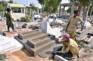 A worker paving a grave with cement in connection with Shab-e-Barat at Tando yosuf Graveyard.