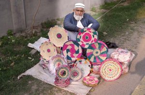 A vendor waiting for handmade bread basket at his roadside setup, attracting passersby in the city streets.
