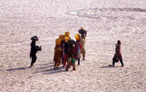 Villager women carry pots filled with water along the banks of the Indus River