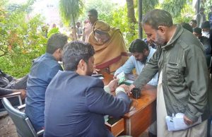 A woman receives financial assistance at the ‘Nigehban’ card activation desk, where payments are being made to eligible women.