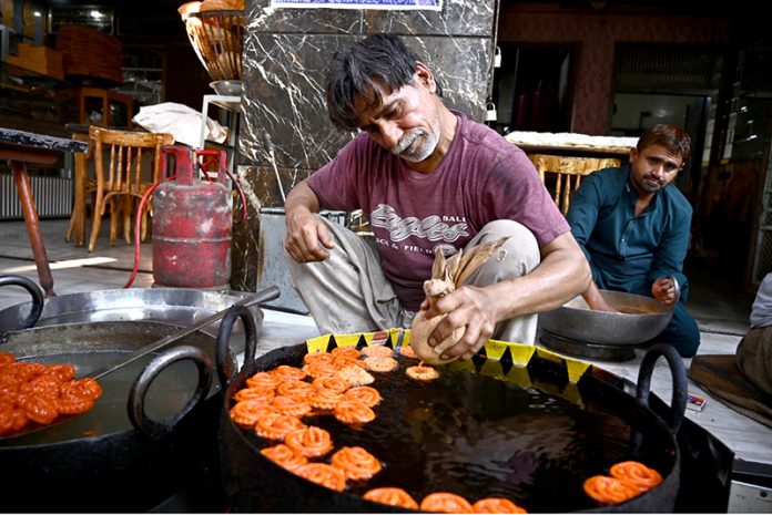 A worker prepares freshly made jalebi, a traditional sweet for iftar, during the holy month of Ramazan at Tower Market