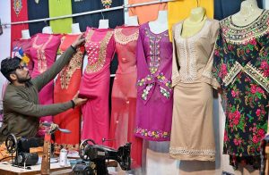 A shopkeeper displaying ladies clothes to attract the customers at Reshamgali.