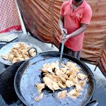 Vendors prepare traditional food items, including Samosas, outside their shop during the holy fasting month of Ramazan