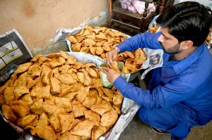 Vendors prepare traditional food items, including Samosas, outside their shop during the holy fasting month of Ramazan